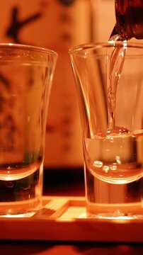 Pouring Japanese Sake Into Clear Shot Glasses at a Tokyo Izakaya