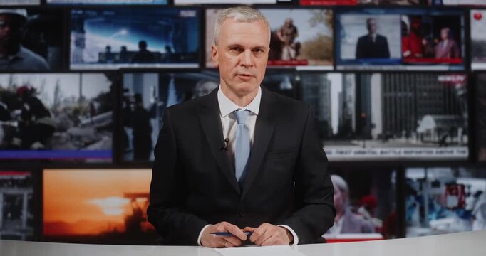 Serious Mature Man Journalist in Blue Tie Sitting at Desk, Presenting Information in Modern TV Studio. Media Broadcasting Featuring Background Mosaic of World Leaders, Rescuers, and War Zones.