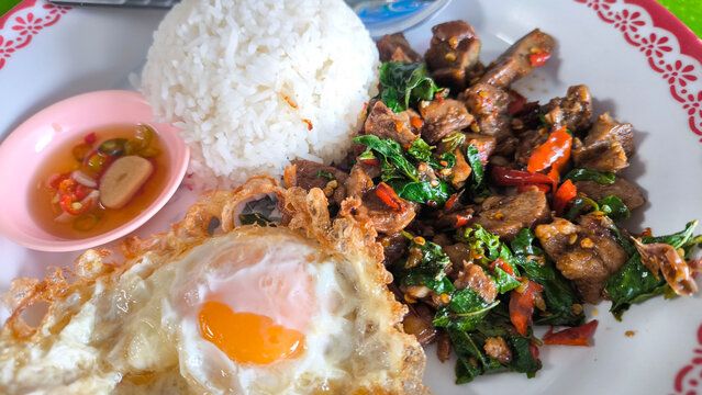 Thai street food stir-fried pork with basil and crispy fried egg served with rice, spicy pad krapow moo with sunny side egg