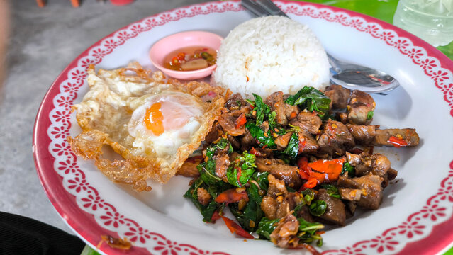 Thai street food stir-fried pork with basil and crispy fried egg served with rice, spicy pad krapow moo with sunny side egg