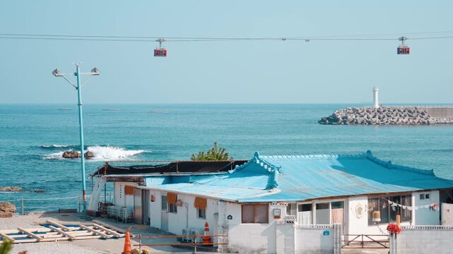 한국 삼척 장호항의 에메랄드빛 바다 위를 가로지르는 해상 케이블카의 풍경 (Scenic view of a marine cable car crossing over the crystal clear emerald ocean in Jangho Port, Samcheok, South Korea)