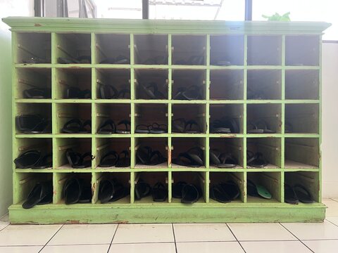 Vintage green wooden shoe rack with multiple compartments neatly storing sandals.