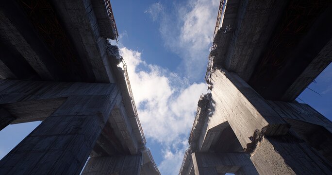 Gaping concrete bridge ruins against a bright, cloudy sky