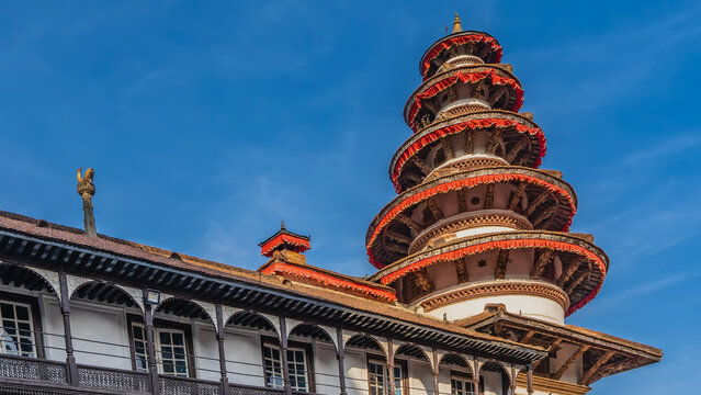 A beautiful multi-tiered pagoda Basantapur Durbar with round roofs decorated with red frills around the edges. The background is a blue sky. Nepal. Kathmandu. Durbar Square.
 