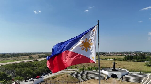 Aerial drone footage orbiting a huge Philippine Independence flag in Imus Heritage Park, Cavite, Philippines. Showcases national pride, historical landmark, and scenic park landscape. Ideal for travel