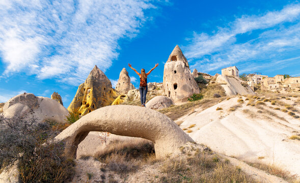 Happy Traveler Standing on Rock with Arms Raised Overlooking Fairy Chimneys in Cappadocia, Turkey