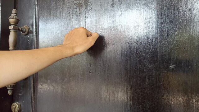 Person Knocking on a Dark Stained Wooden Door Entrance