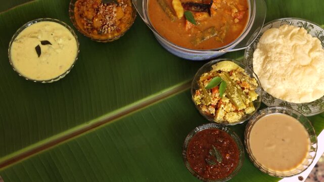 Traditional Onam Vishu sadhya rice Sambar, Rasam, parippu dal curry ghee Pappadom Payasam on banana leaf Onam Pongal Diwali festival vegetarian food Kerala Tamil Nadu South India. 4k video footage