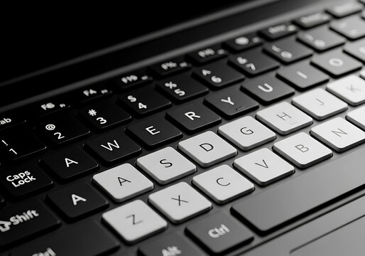 Close up view of a modern black laptop keyboard showing the qwerty layout with white keys and dark background lighting