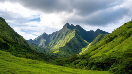 Obraz premium Lush green mountains under a cloudy sky with sunlight casting shadows on the peaks and valleys in a tranquil natural landscape.