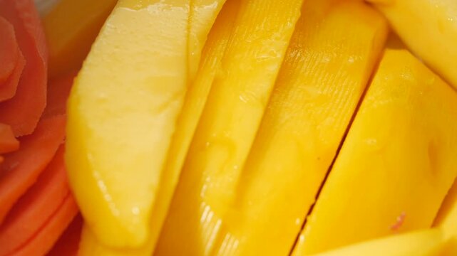 Fresh sliced mango pieces macro shot with slow camera pan across juicy yellow fruit texture.