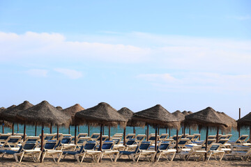 Fototapeta premium Parasols and sunbeds on a beach on the Costa del Sol, Andalusia, Spain 