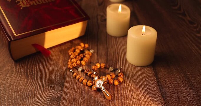 Sacred bible and olive wood rosary with white candles on white background for illustrating christian faith and religious devotion.