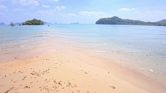 Narrow sandbank extending into tranquil turquoise water with distant islets