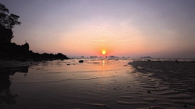 Low tide sunrise over rippled wet sand with distant limestone islands