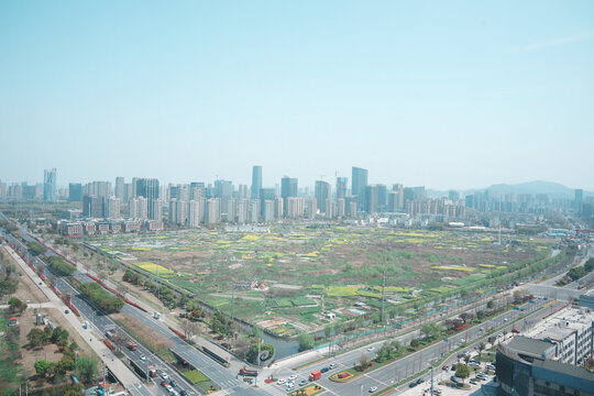 Urban fringe undeveloped land plot adjacent to high-rise building cluster under clear sky