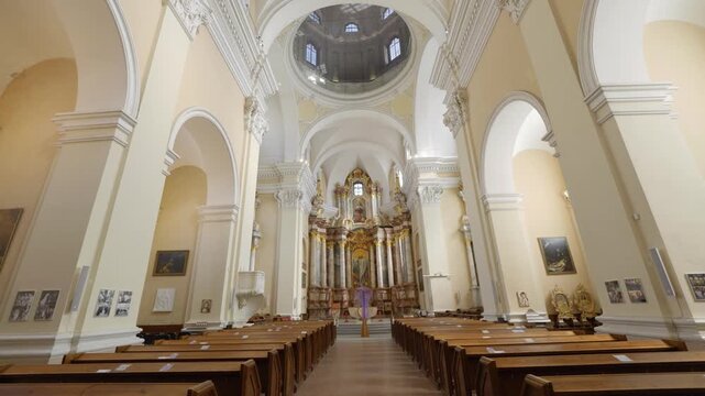 Vilnius, Lithuania &mdash; April 4, 2026: Sliding camera movement inside the historic Church of St. Casimir featuring the ornate altar and nave