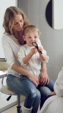 Ophthalmologist in clinic explains diagnosis about girl's eyesight - child plays
