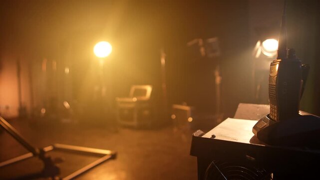 Camera slider on studio floor with warm lights, smoke, and backstage equipment. Concept of video production, filming technology, concert setup, media, and creative industry.