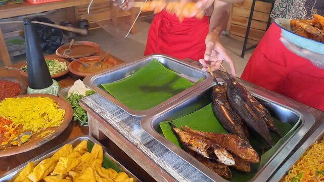 PAMEKASAN, INDONESIA - DECEMBER 17, 2025: Handheld footage inside a traditional Javanese joglo-style restaurant, showcasing authentic Indonesian cuisine, local vegetables, fish dishes, sambal, lalapan