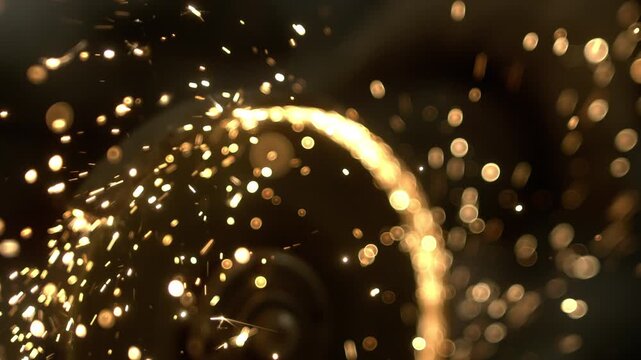 Gold sparks move and swirl in a round pattern. The bright lights create an interesting visual effect. This takes place in a dark area where the sparks stand out clearly.