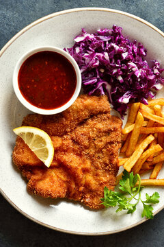 Schnitzel with potato fries, red cabbage salad and sauce