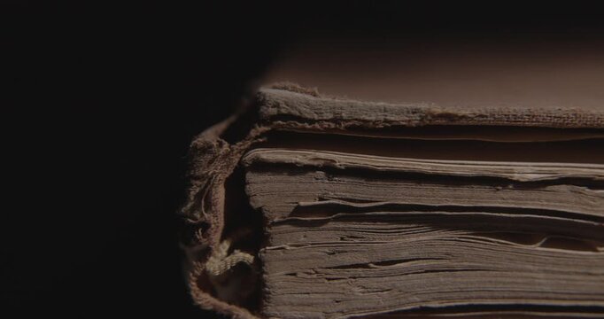 Closeup of pages of an old weathered vintage book in local light. Historical knowledge archive library concept. Slider macro 4K video. 