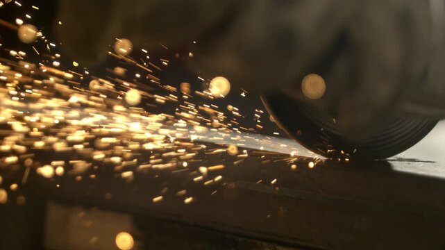 A person grinds metal to shape and smooth the surface. Sparks fly from the metal as the tool makes contact. The setting is a workshop with a focus on craftsmanship.