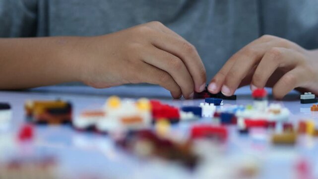 Child playing and building with colorful toy bricks, plastic blocks.	
