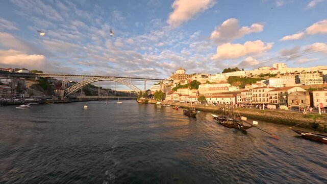 FPV drone rising from Douro River in Porto Portugal passing over a boat and revealing Dom Lu&iacute;s I Bridge and city at sunset.
4K high quality immersive cinematic FPV footage.