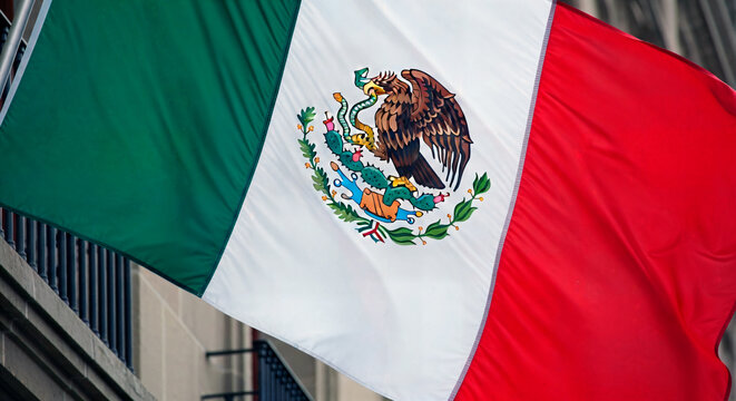 A flag fluttering in the wind. A close-up of the Mexican banner featuring the emblem of the eagle and the snake. Patriotism and a national symbol.