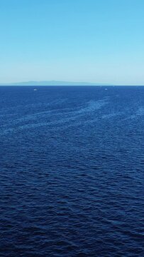 Wide view of tranquil blue ocean with distant island and clear sky, captured from the coast of Bohol, Philippines.