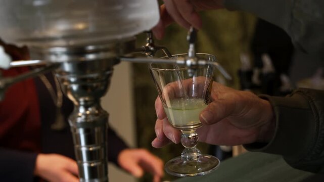 Preparing green absinthe with fountain as drink turns milky louche effect