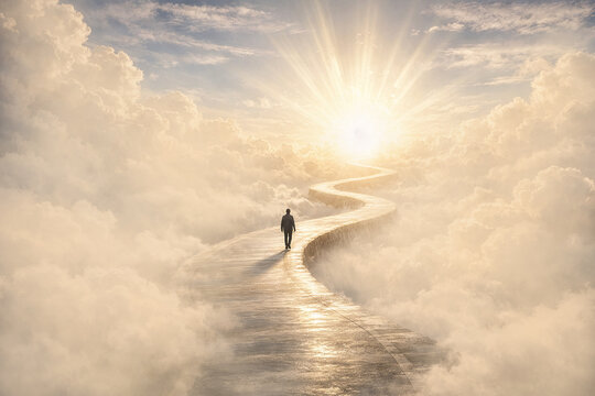 Silhouette of a man walking on winding path through the clouds, ending at a brilliant light in the distance. It symbolises heaven, afterlife, a near-death experience, path to a goal and bright future.