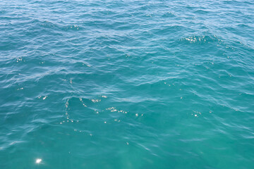 Fototapeta premium Turquoise seawater texture with ripples and sun glare. Beautiful blue ocean water background