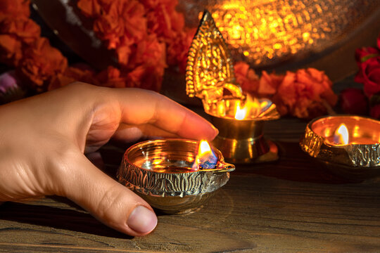 Hand with Diwali lamp diya or Deepavali or Deepawali. Hindu festival of lights. Celebrating in Indian religions Jainism and Sikhism. Offering to the gods, a spiritual rite. Close up view, out of focus