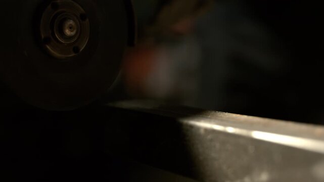 A metalworking session shows a grinding tool shaping a piece of metal in a workshop. Sparks fly as the tool makes contact with the surface. The process highlights skilled craftsmanship.