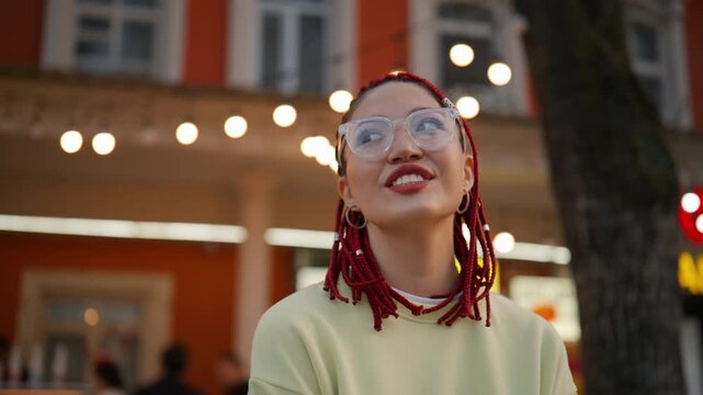 Happy young woman with red dreadlocks smiling on a city street