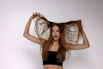 Fototapeta premium Young woman playfully poses with long hair on a plain background during a studio photoshoot session