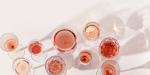 Various glasses of rose wine or champagne sweet and dry, top view. Light alcohol sparkling drink for party. Flat lay minimal style banner, summer day. Crystal wine glasses still life background © yrabota