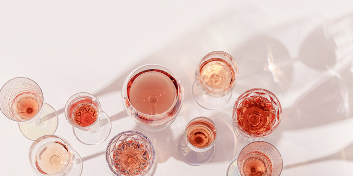 Various glasses of rose wine or champagne sweet and dry, top view. Light alcohol sparkling drink for party. Flat lay minimal style banner, summer day. Crystal wine glasses still life background