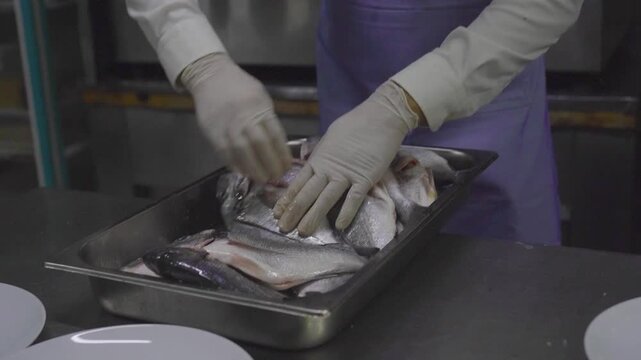Professional chef preparing fresh raw sea bream fish in restaurant kitchen