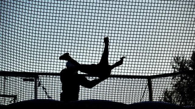 Silhouettes of people flying in a wind tunnel, with an instructor assisting