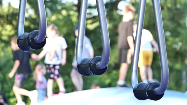 Playground monkey rings with blurry kids playing outdoors on a summer day