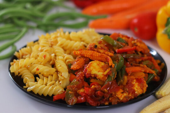 Veg jalfrezi with pasta fusion meal on plate close up