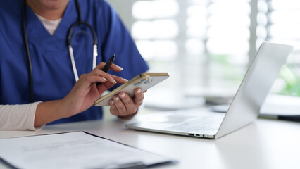 Fototapeta premium Healthcare professional using smartphone medical setting desktop computer work nurse doctor physician staff technology digital device online communication patient data management office desk
