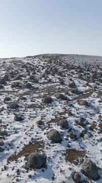 Vertical top-down drone flight towards giant spherical stone concretions in the Torysh Valley. A winter landscape of Mangystau, where the snow-covered remains of the ancient Tethys Ocean create