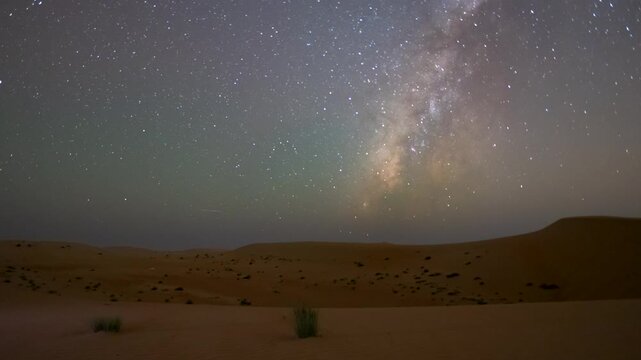 Wide angle lense time lapse of night Stars milky way moving across clear night sky in empty desert sand dune in the winter.