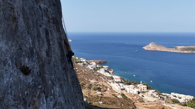 Extreme sports adventure: Man rock climbing on a majestic cliff over the Mediterranean ocean in Kalymnos.