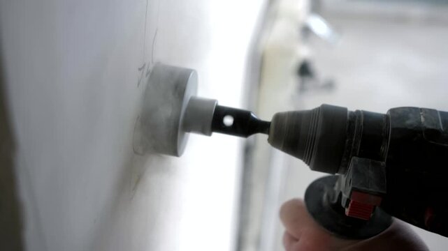 Creating round wall openings using hole saw for socket mounting during interior renovation.